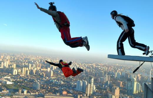 BASE jumpers leap off the edge of a building over a city skyline.