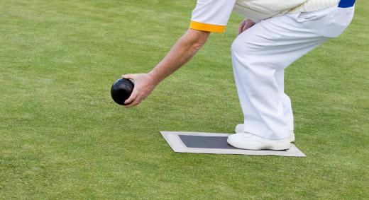 Players take turns rolling a ball in lawn bowling.